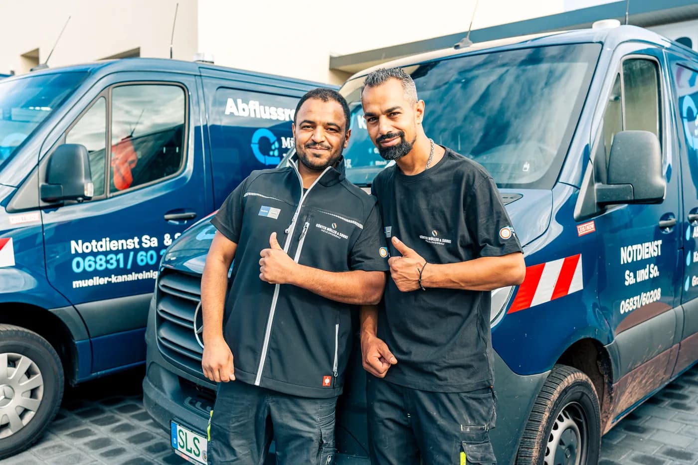 Zwei Monteure der Müller GmbH vor einem beschrifteten Einsatzfahrzeug
