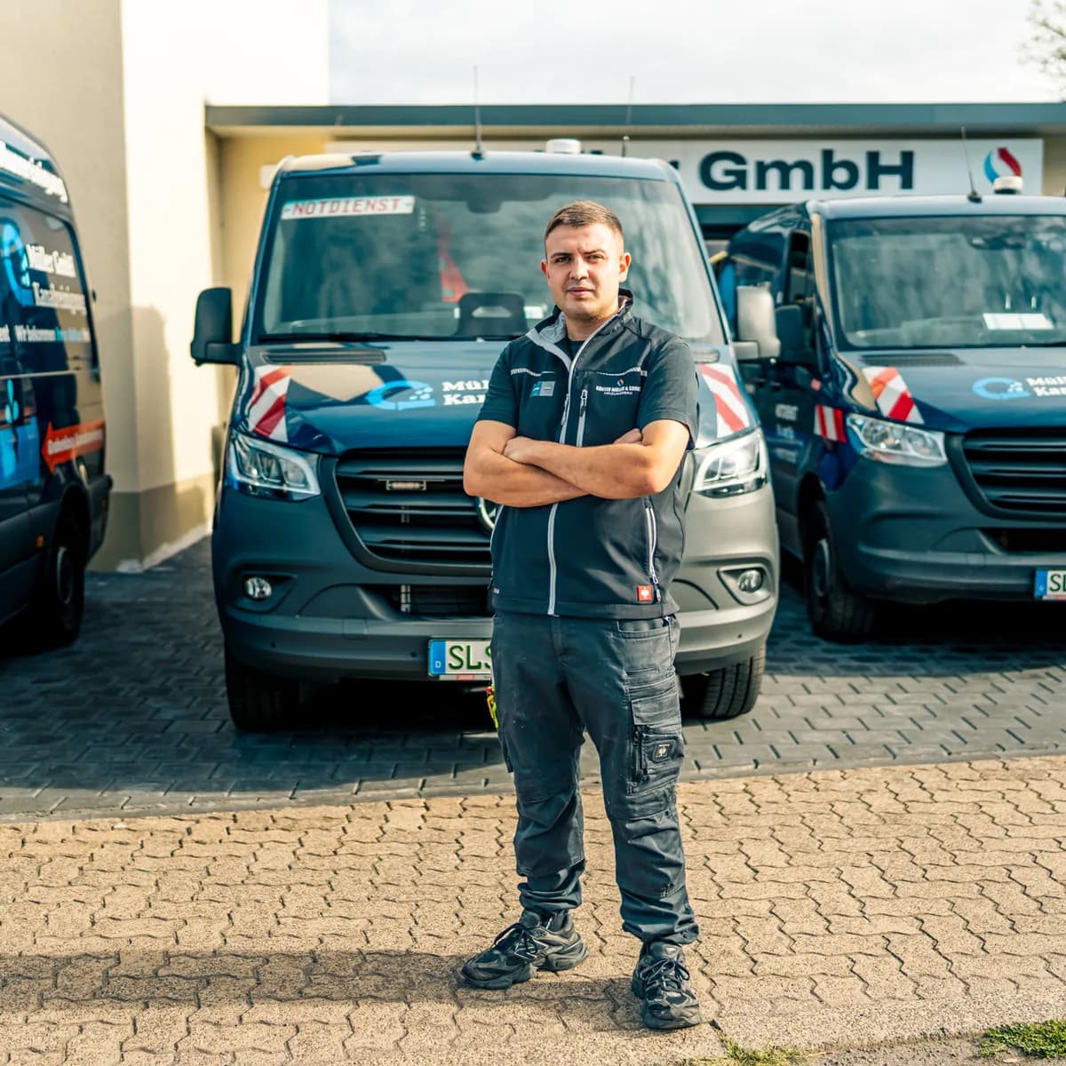 Monteur der Müller GmbH vor den Einsatzfahrzeugen auf dem Betriebshof